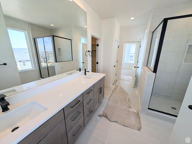full bath with double vanity, a shower stall, and a sink