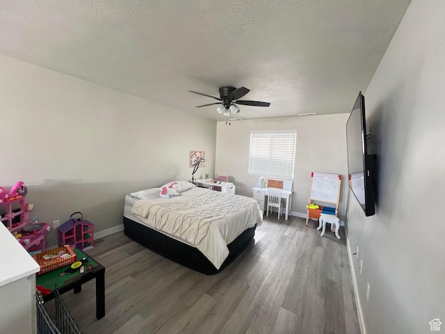 bedroom with ceiling fan, a textured ceiling, and hardwood / wood-style flooring