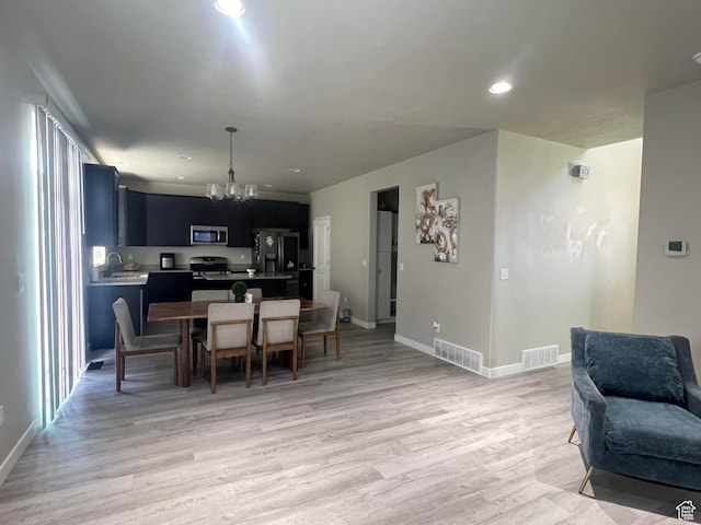 dining room with a chandelier, sink, and light hardwood / wood-style floors