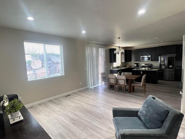 living room with an inviting chandelier, sink, and light hardwood / wood-style flooring