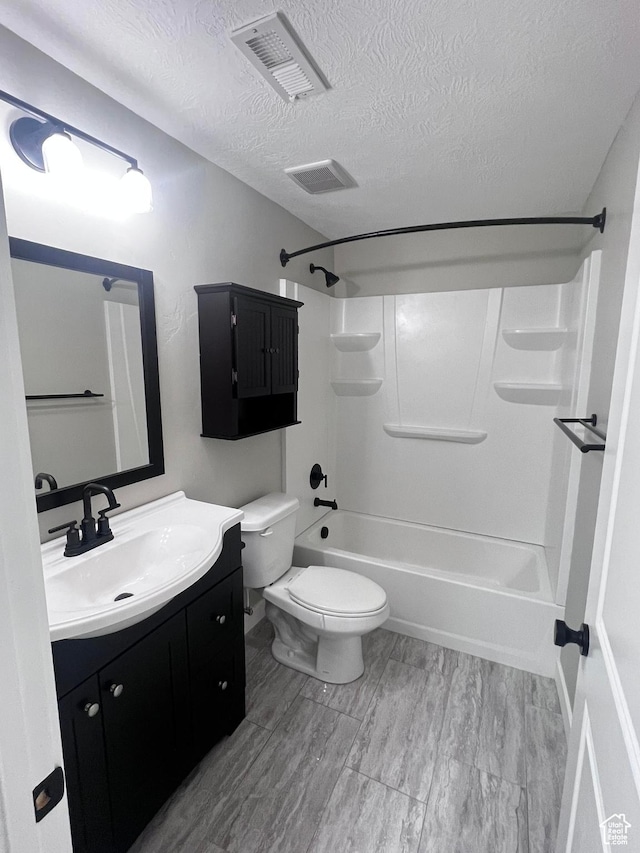 full bathroom with vanity, a textured ceiling, wood-type flooring, washtub / shower combination, and toilet