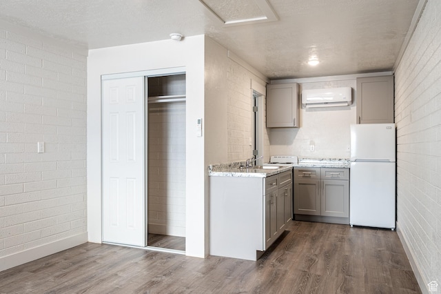 1180 S Cove View Rd, Richfield, UT 84701 - kitchen featuring white fridge, brick wall, a wall mounted air conditioner, and hardwood / wood-style flooring