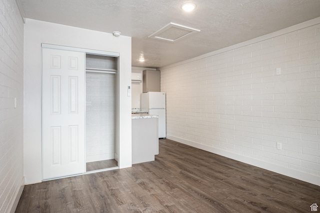 1180 S Cove View Rd, Richfield, UT 84701 - unfurnished bedroom featuring dark hardwood / wood-style flooring, brick wall, a textured ceiling, white fridge, and a closet