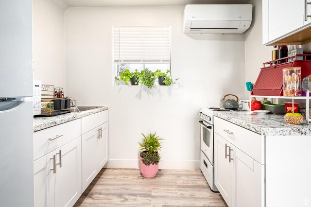 1180 S Cove View Rd, Richfield, UT 84701 - kitchen featuring a wall mounted AC, light hardwood / wood-style flooring, white cabinets, and white appliances