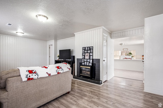 1180 S Cove View Rd, Richfield, UT 84701 - living room featuring a tiled fireplace, wood walls, a textured ceiling, and hardwood / wood-style flooring