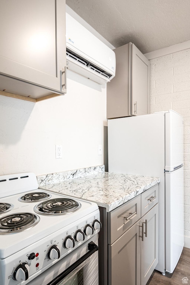 1180 S Cove View Rd, Richfield, UT 84701 - kitchen with light stone counters, dark hardwood / wood-style floors, a wall unit AC, white appliances, and gray cabinets
