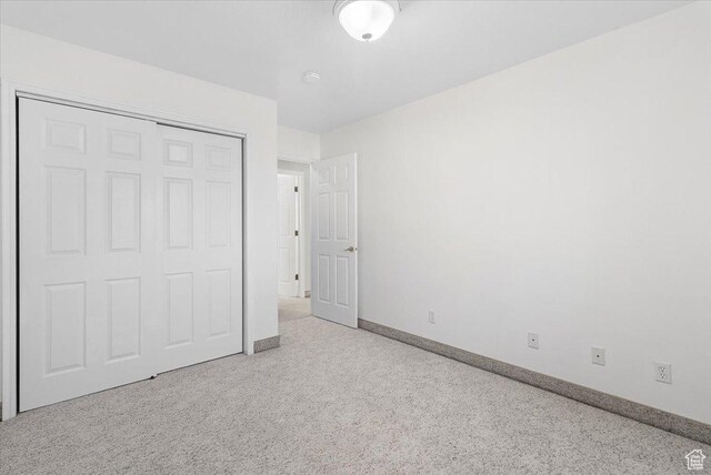 unfurnished bedroom featuring light carpet and a closet