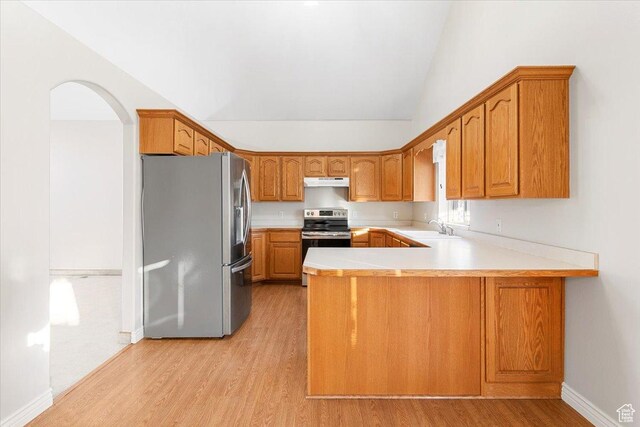 kitchen featuring kitchen peninsula, appliances with stainless steel finishes, light hardwood / wood-style flooring, and lofted ceiling