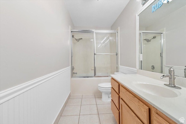 full bathroom featuring tile patterned flooring, vanity, toilet, and bath / shower combo with glass door