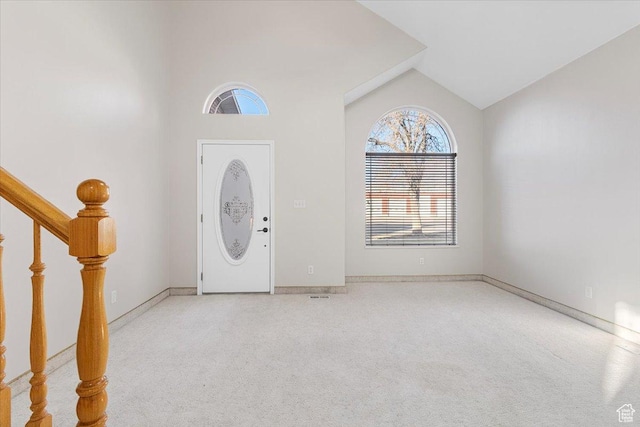 foyer entrance with light carpet and high vaulted ceiling