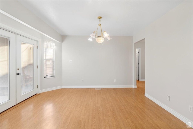 unfurnished room featuring a chandelier, french doors, and light wood-type flooring