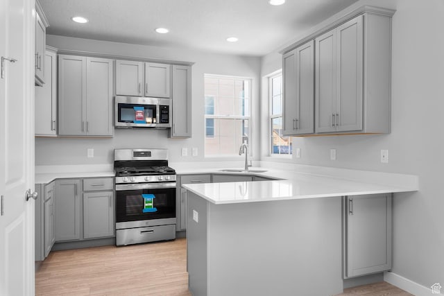 6636 W Prairie Fire Ln Unit 733, Herriman, UT 84096 - kitchen with gray cabinetry, sink, light wood-type flooring, kitchen peninsula, and stainless steel appliances