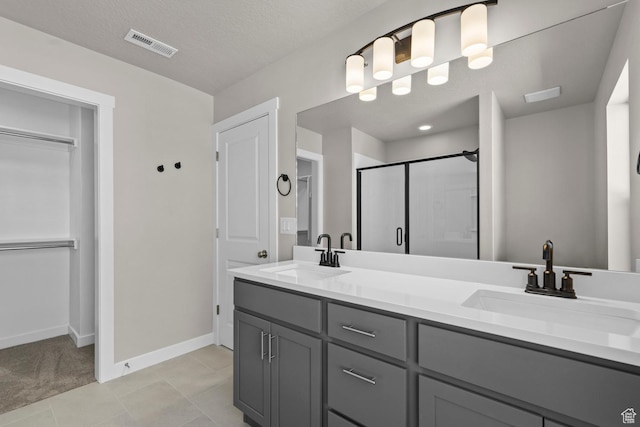 bathroom featuring tile patterned floors, vanity, an enclosed shower, and a textured ceiling