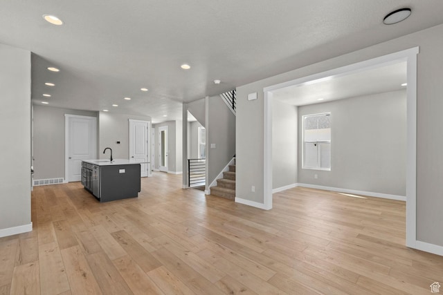 unfurnished living room featuring light wood-type flooring and sink