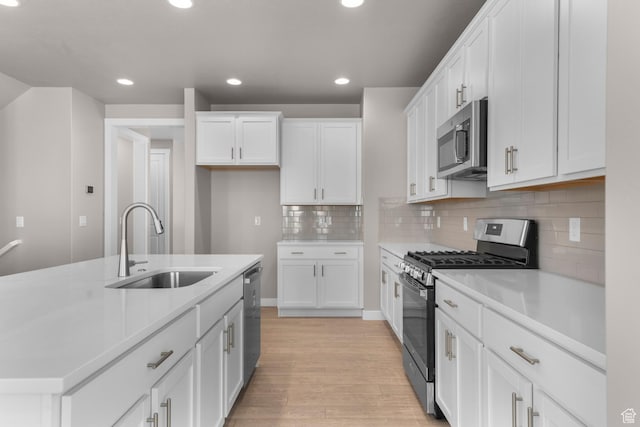 kitchen featuring light wood-type flooring, stainless steel appliances, white cabinetry, and sink