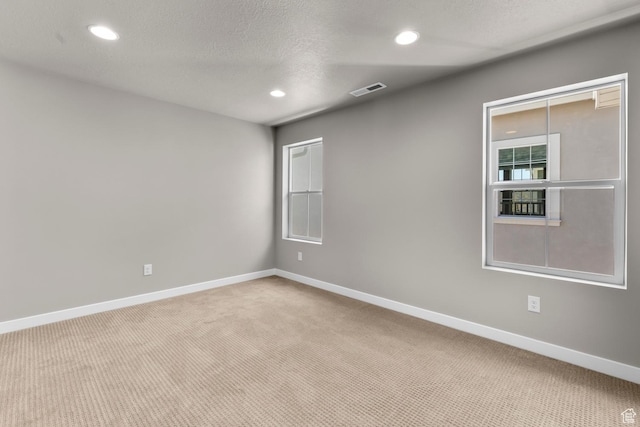 carpeted empty room featuring a textured ceiling