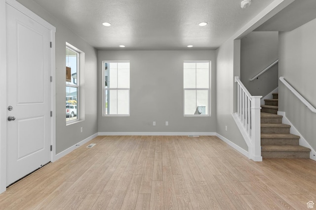 foyer with a textured ceiling and light hardwood / wood-style flooring
