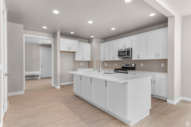 kitchen with white cabinets, sink, a kitchen island with sink, and appliances with stainless steel finishes
