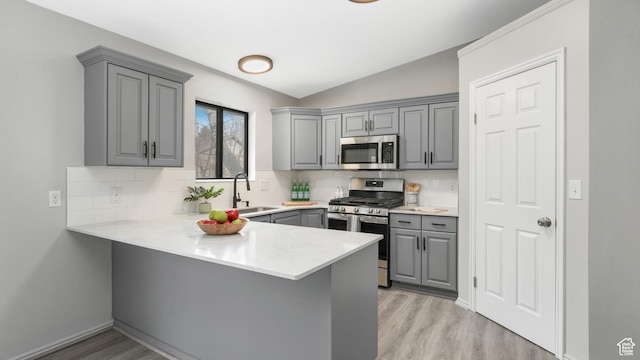 1583 E 1500 N, Logan, UT 84341 - kitchen featuring lofted ceiling, sink, light wood-type flooring, kitchen peninsula, and stainless steel appliances