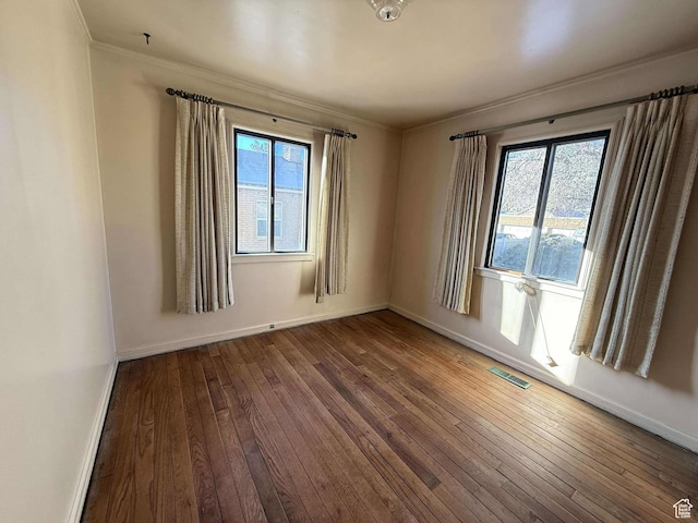 unfurnished room with hardwood / wood-style floors, a wealth of natural light, and crown molding