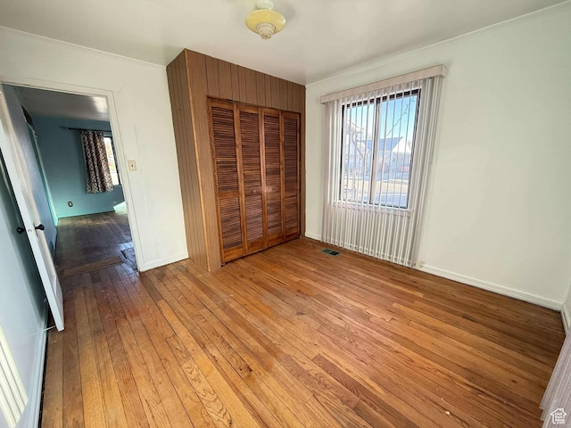 unfurnished bedroom with a closet, ornamental molding, and light hardwood / wood-style flooring
