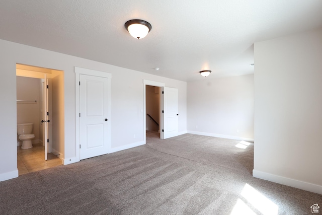 carpeted spare room with a textured ceiling and baseboards