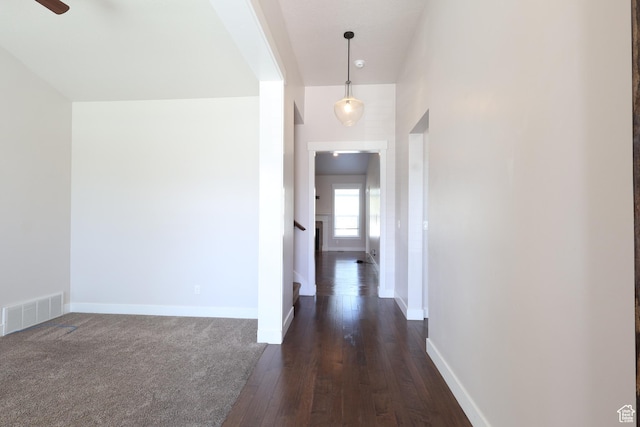 corridor featuring visible vents, baseboards, and dark wood-style floors