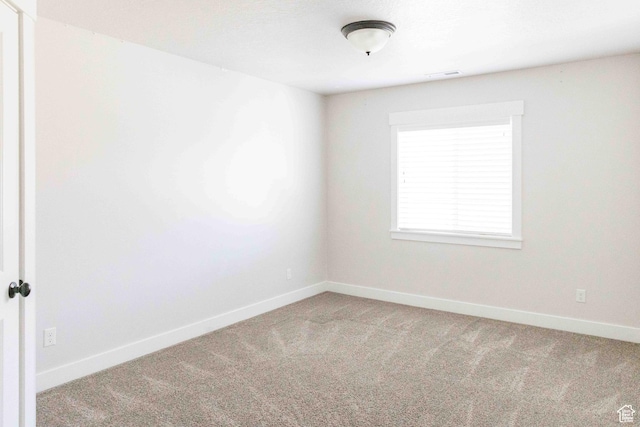 unfurnished room with carpet flooring, visible vents, and baseboards