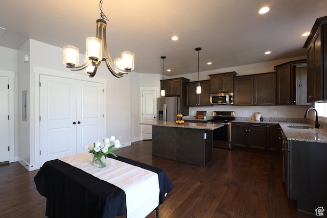 kitchen with dark brown cabinetry, dark stone countertops, a kitchen island, appliances with stainless steel finishes, and a sink