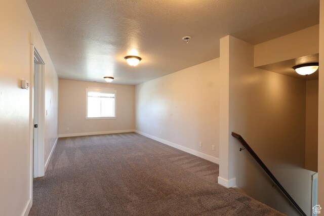 unfurnished room with a textured ceiling, baseboards, and carpet floors