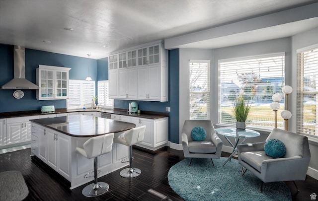 4487 W Tee Box Dr, South Jordan, UT 84009 - kitchen featuring wall chimney exhaust hood, dark countertops, glass insert cabinets, a kitchen island, and white cabinetry