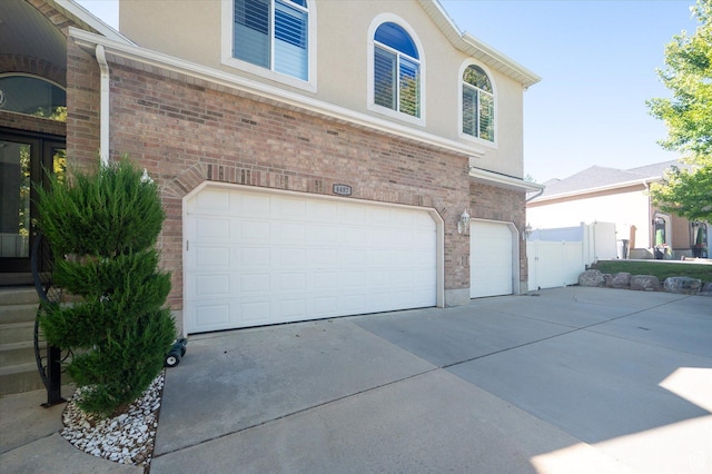 4487 W Tee Box Dr, South Jordan, UT 84009 - view of side of home with a garage, driveway, stucco siding, and brick siding