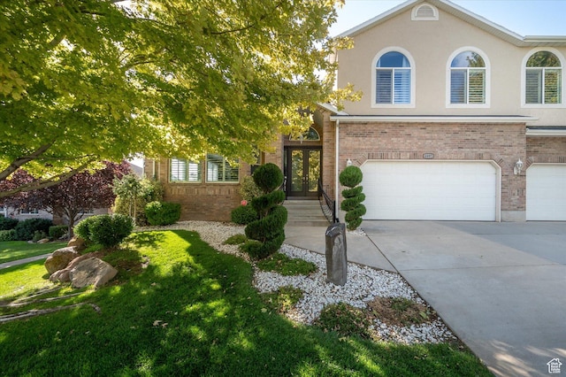 4487 W Tee Box Dr, South Jordan, UT 84009 - view of front of property with french doors, a garage, driveway, brick siding, and stucco siding