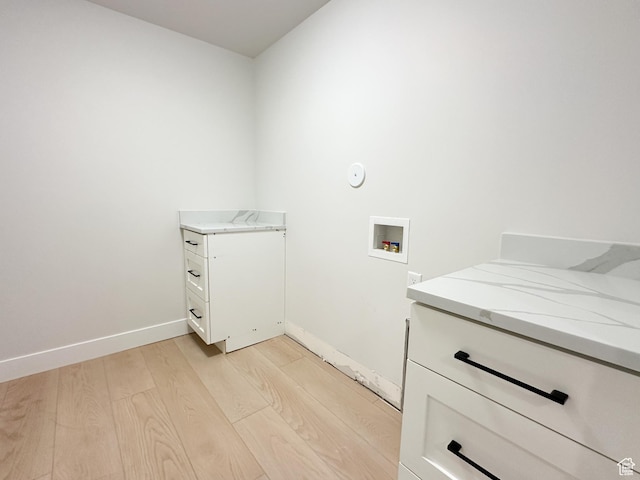 clothes washing area with cabinets, light wood-type flooring, and hookup for a washing machine