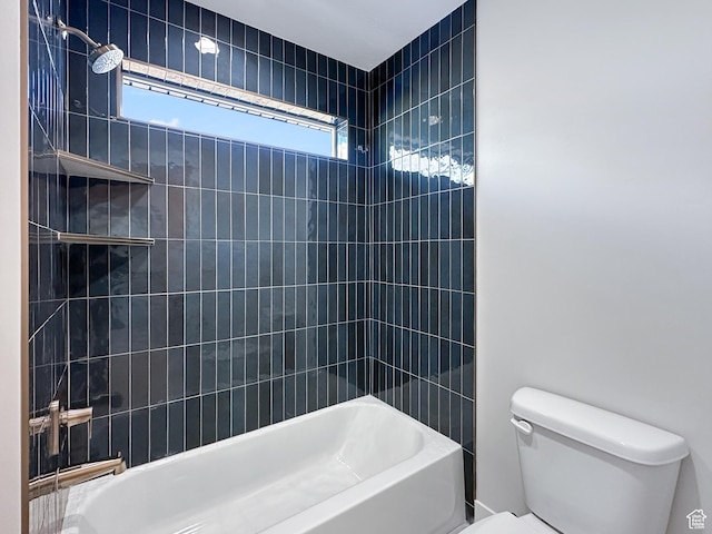 bathroom with toilet and tiled shower / bath