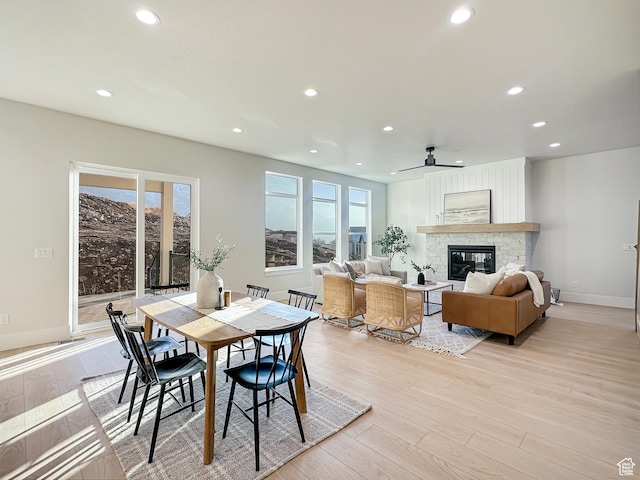 dining space with a fireplace, light hardwood / wood-style floors, and ceiling fan