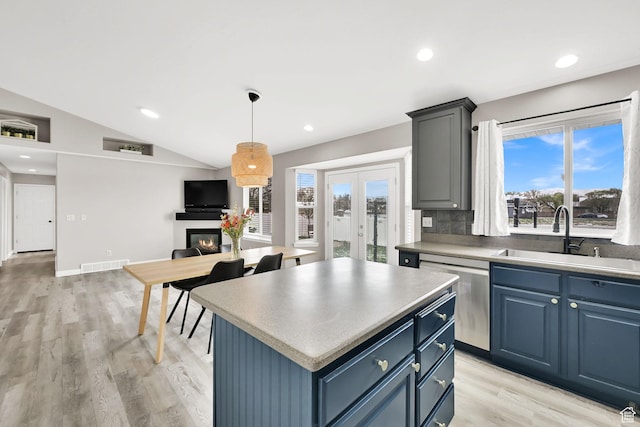 kitchen with open floor plan, vaulted ceiling, a sink, visible vents, and dishwasher