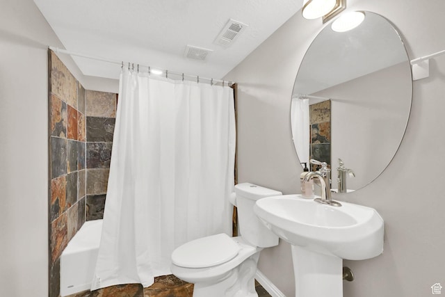 full bath featuring toilet, a sink, stone finish flooring, and visible vents