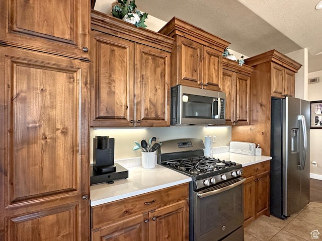 1313 N 250 E, Brigham City, UT 84302 - kitchen with stainless steel appliances, brown cabinets, light tile patterned floors, light countertops, and a textured ceiling