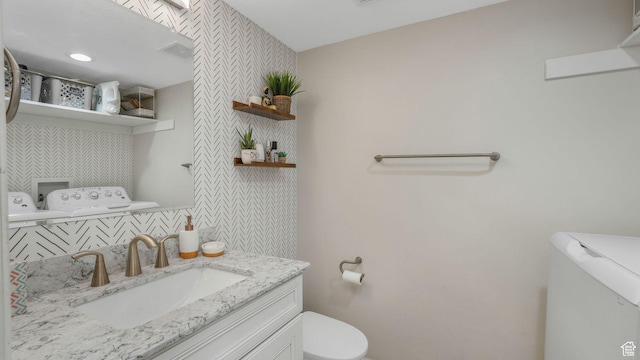 bathroom with separate washer and dryer, vanity, and toilet