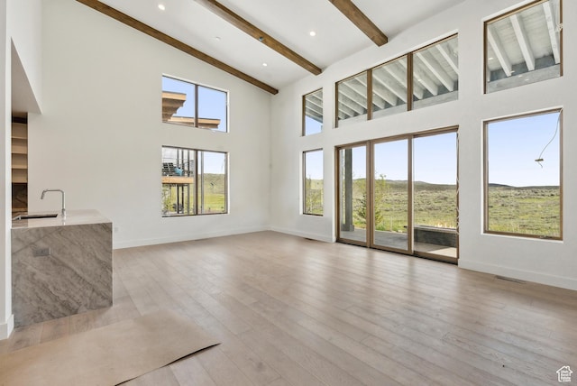 5758 Cobalt Cir Unit 12, Park City, UT 84098 - unfurnished living room with beam ceiling, a high ceiling, a sink, baseboards, and light wood finished floors
