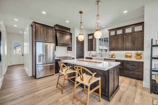 1333 Sage Way Unit 45, Francis, UT 84036 - kitchen with dark brown cabinetry, a center island, hanging light fixtures, high quality appliances, and light wood-type flooring