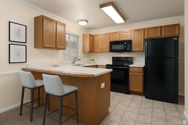 kitchen featuring a peninsula, black appliances, light countertops, a sink, and a breakfast bar area