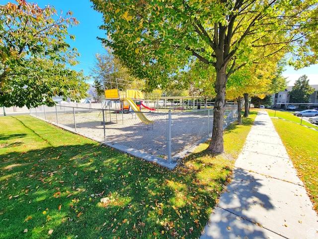 view of community with playground community, fence, and a lawn