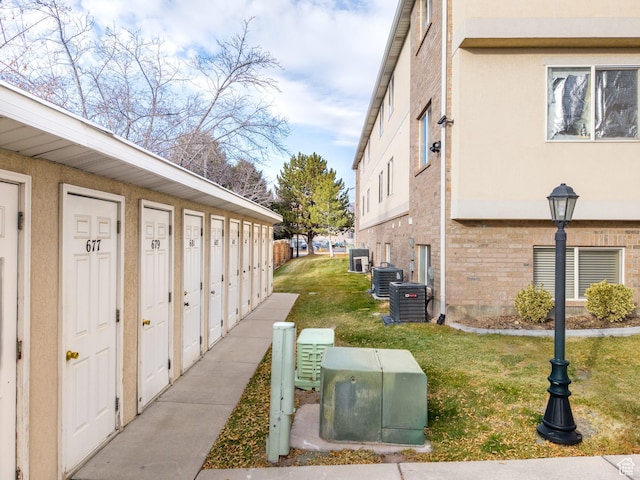 view of home's exterior featuring mail area, a yard, brick siding, and central AC