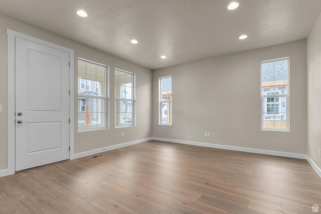 interior space featuring light wood-type flooring, visible vents, a textured ceiling, recessed lighting, and baseboards