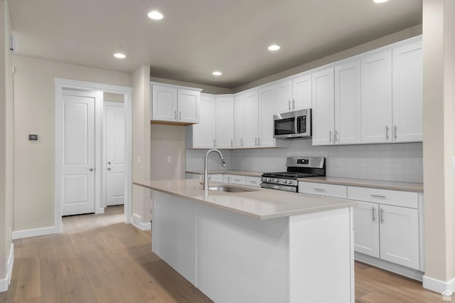 kitchen with a sink, light wood-style flooring, backsplash, and stainless steel appliances