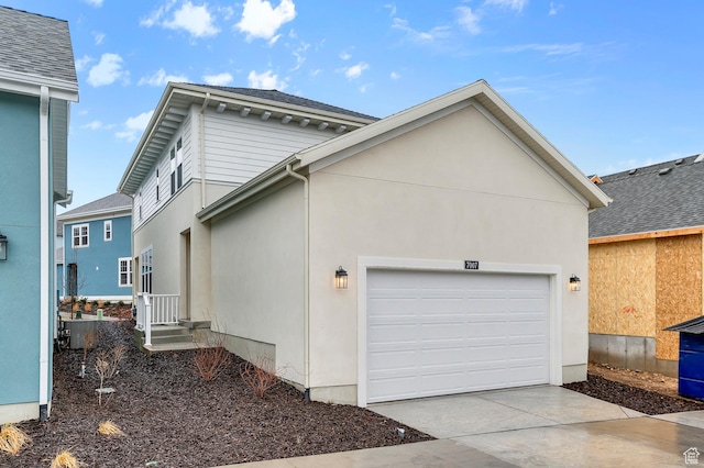 view of side of home featuring a garage, driveway, and stucco siding