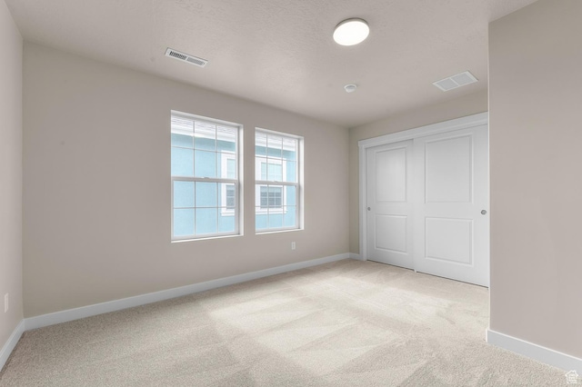 unfurnished bedroom with baseboards, visible vents, a closet, and light carpet