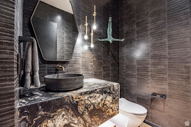 bathroom with toilet, tile walls, and vanity